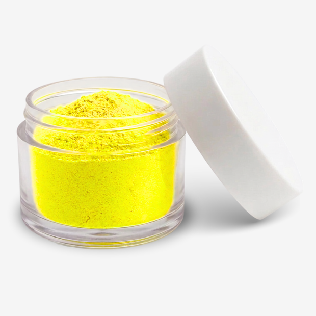 A small clear plastic jar filled with bright yellow food colouring powder, shown with its white lid leaning against it on a clean white background.