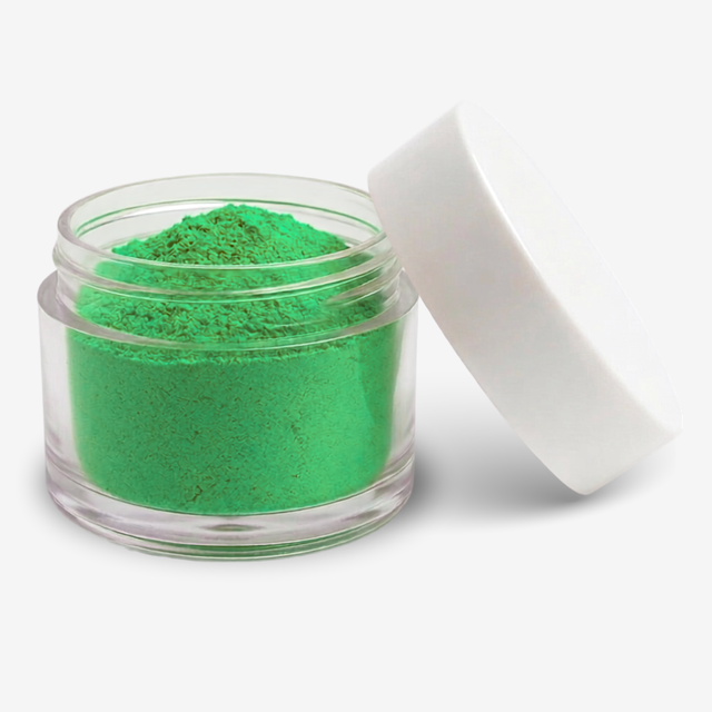 A small clear plastic jar filled with apple green food colouring powder, shown with a white lid leaning against it on a light gray background.