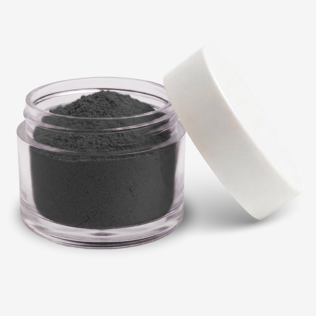 A small clear plastic jar filled with a black food colouring powder, with a white screw-on lid leaning against it on a clean white background.