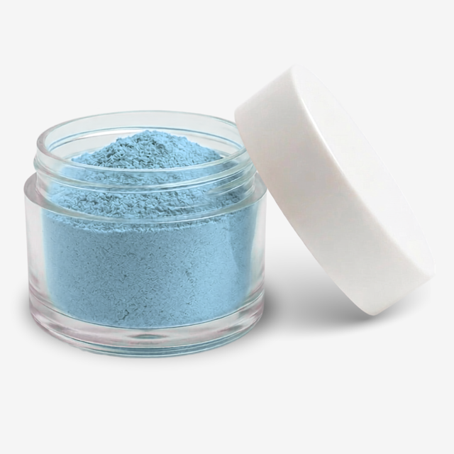 A small clear round jar filled with blizzard blue powder, shown with a white lid leaning against it on a clean white background.