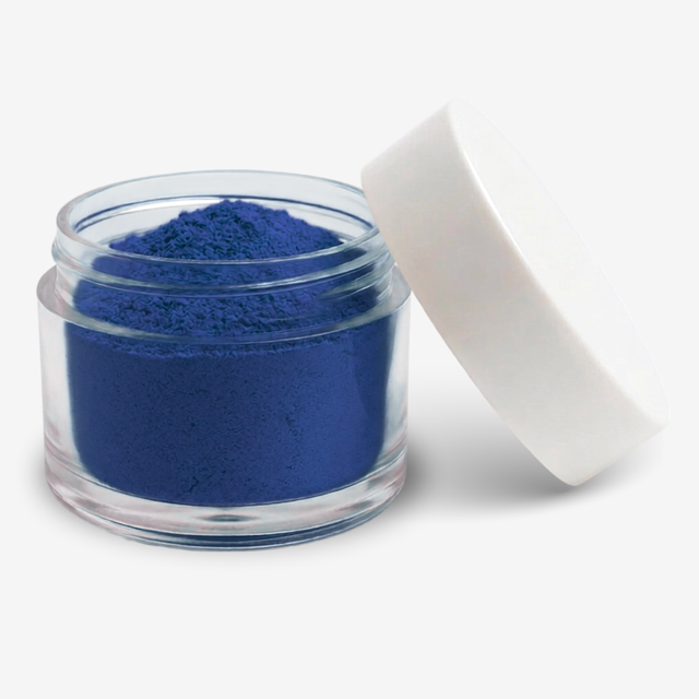 A small clear plastic jar filled with blue food colouring powder, shown with a white screw-on lid leaning against it on a clean white background.