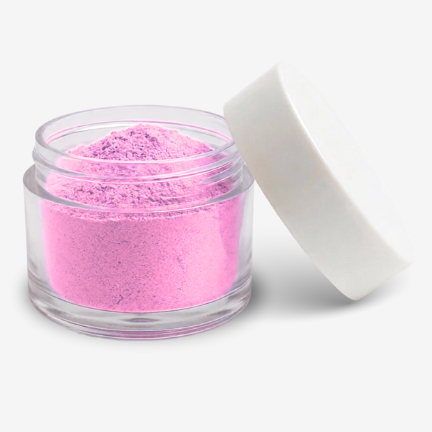 A small clear plastic jar filled with carnation pink food colouring powder, shown with a white screw-top lid leaning against it on a clean white background.