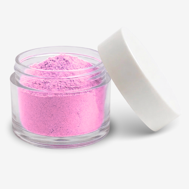 A small clear plastic jar filled with carnation pink food colouring powder, shown with a white screw-top lid leaning against it on a clean white background.