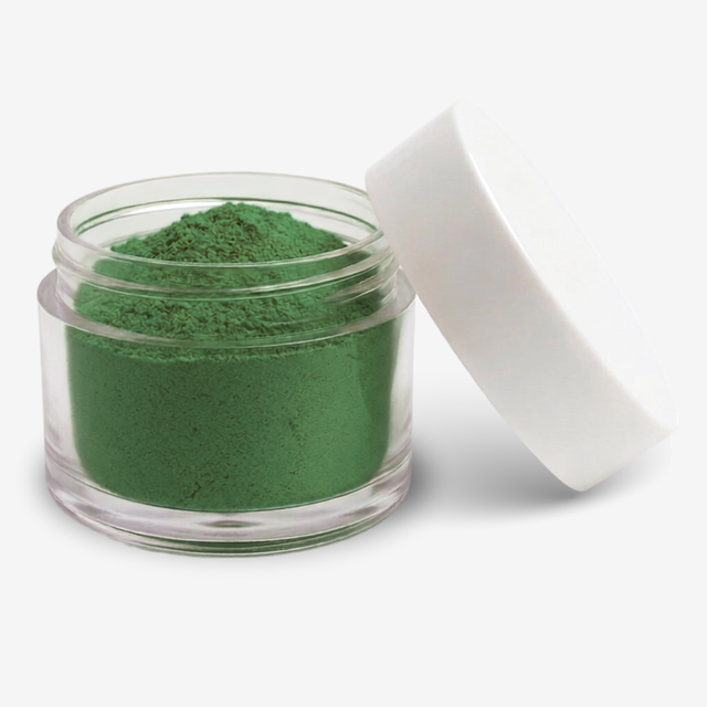A small clear plastic jar filled with green food colouring powder, shown with a white lid leaning against it on a clean white background.