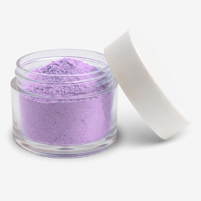 A small clear round jar filled with lavender food colouring powder, shown with a white lid leaning against it on a clean white background.