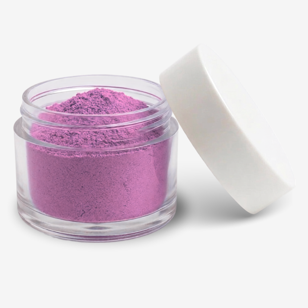 A small clear jar filled with bright pink-purple food colouring powder, shown with a white lid leaning against it on a clean white background.