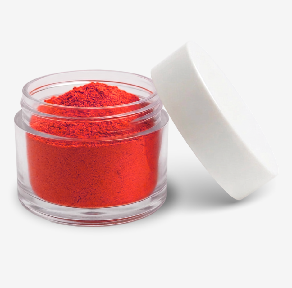 A small clear plastic jar filled with red food colouring powder, shown with its white lid leaning against it on a clean white background.