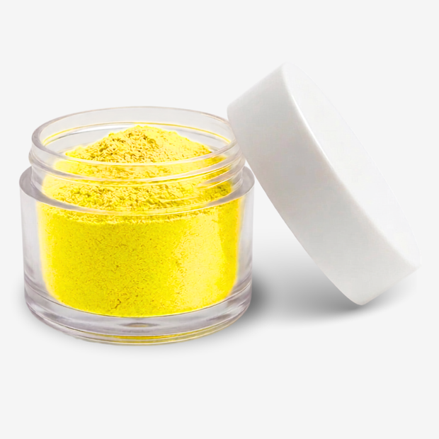 A small clear jar filled with yellow food colouring powder, shown with its white lid leaning against it on a clean white background.